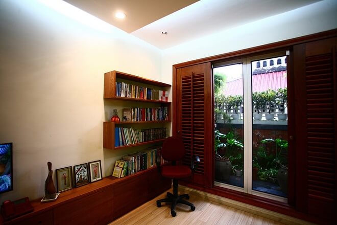 Phòng ngủ kết hợp phòng đọc sách có khung cửa nhìn ra khoảng xanh ở ban công. Hệ cửa lùa và vách nhẹ giúp tận dụng tối đa diện tích, sau sửa chữa cải tạo nhà ống này.