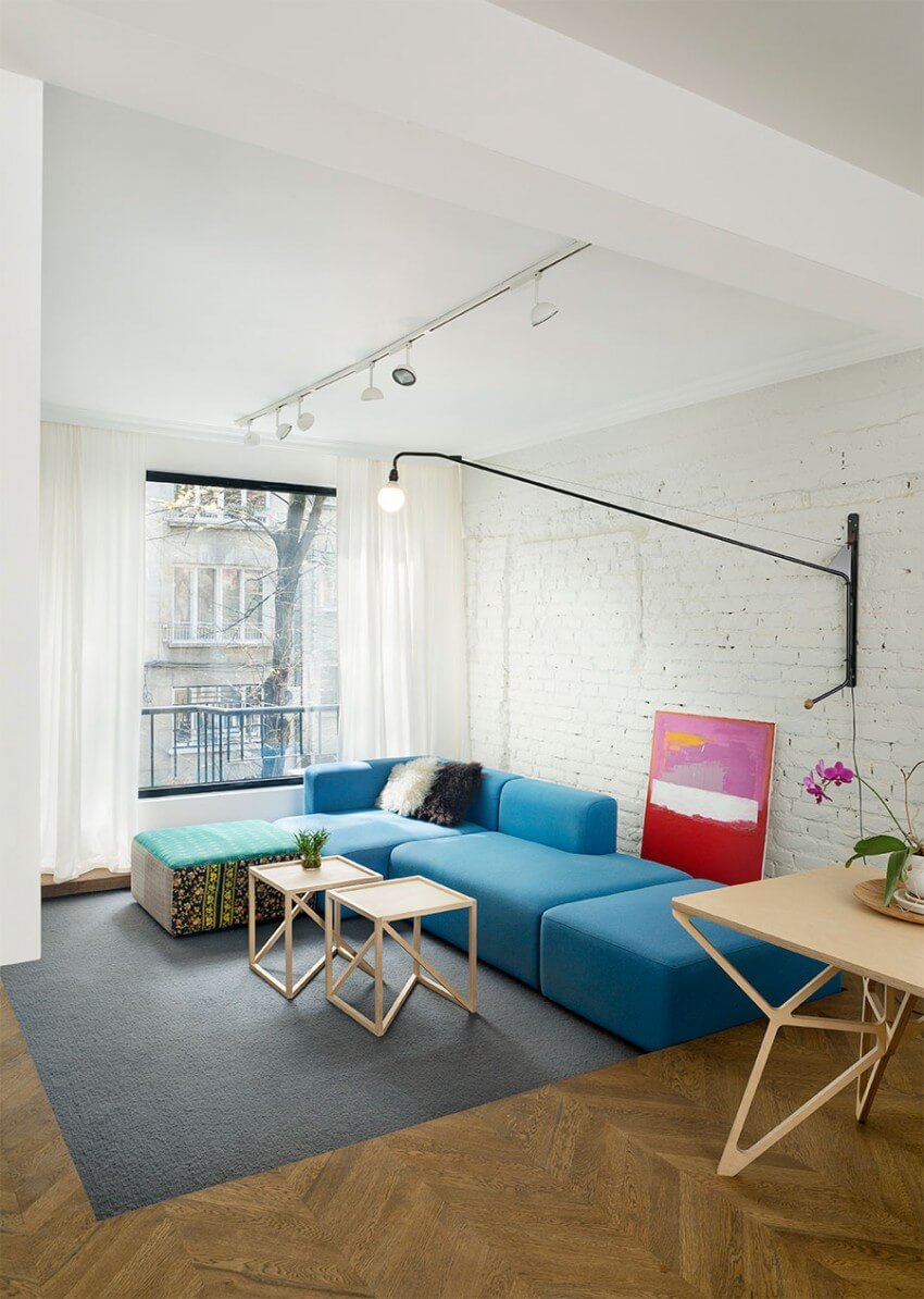 Phòng khách khá rộng sắp xếp được nhiều thứ. Một bộ ghế sofa màu xanh dương được đặt sát bức tường gạch sau khi cải tạo nhà, được sơn màu trắng.
